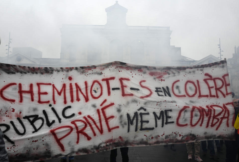 Rail workers demonstrate during a mass strike in Lille, northen France, Thursday, Dec. 5, 2019. Workers across the public sector fear President Emmanuel Macron's reform will force them to work longer and shrink their pensions. Banner reads: "Angry railway worker, private and public same fight". (AP Photo/Michel Spingler)