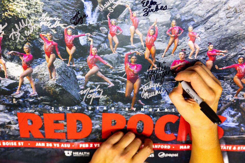 Amelie Morgan signs a poster after the Red Rocks Preview at the Jon M. Huntsman Center in Salt Lake City on Friday, Dec. 15, 2023. | Megan Nielsen, Deseret News