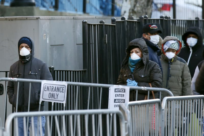 Personas utilizando mascarillas hacen fila para realizarse pruebas por coronavirus fuera del Hospital Center, en el vecindario de Queens, Nueva York