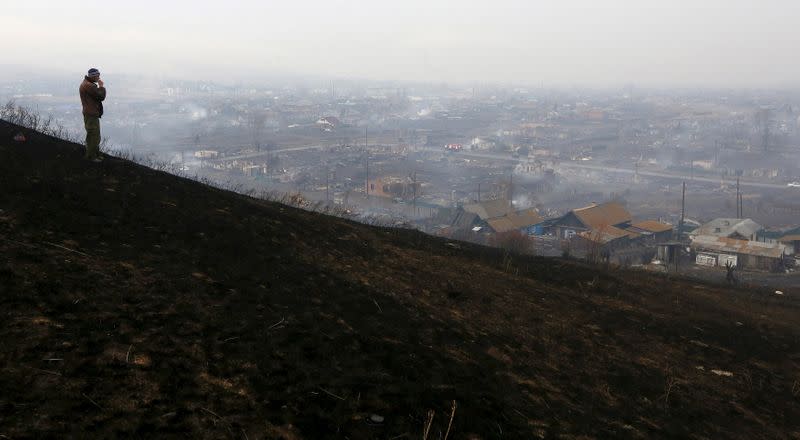 FILE PHOTO: Man looks downhill at the settlement of Shyra, damaged by recent wildfires, in Khakassia region