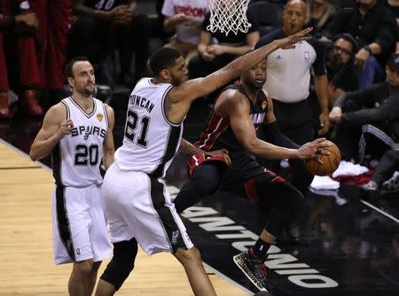 Dwyane Wade (3) passes off under the basket against San Antonio Spurs forward Tim Duncan (21) in game five of the 2014 NBA Finals at AT&T Center. Jun 15, 2014; San Antonio, TX, USA; Soobum Im-USA TODAY Sports