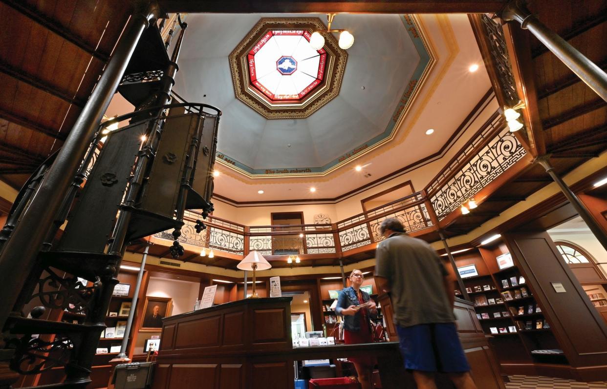 A spiral staircase stands next to the circulation desk at the Thayer Memorial Library. The Peace window is above.