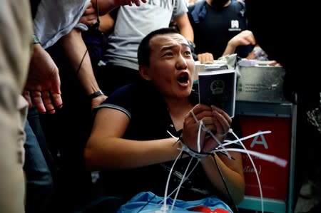 FILE PHOTO: Fu Guohao, reporter of Chinese media Global Times website, is tied by protesters during a mass demonstration at the Hong Kong international airport, in Hong Kong