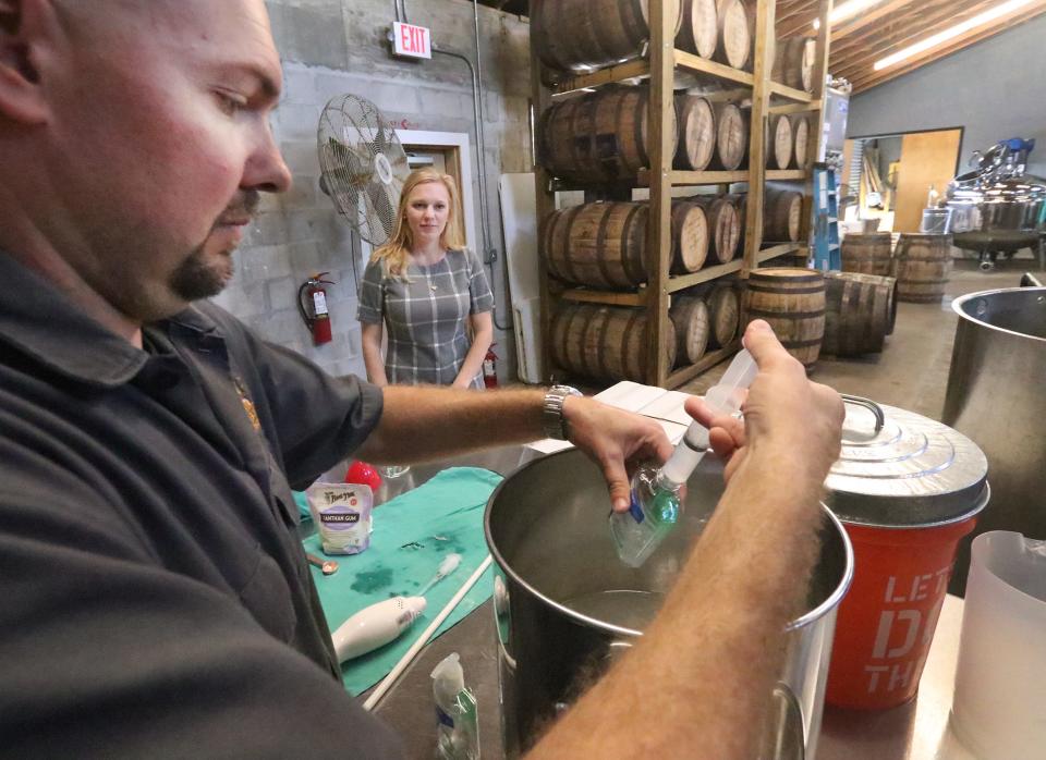 Copper Bottom Craft Distillery owner Jeremy Craig fills a small bottle with hand sanitizer while his wife and co-owner Jenni Craig looks on, Wednesday March 18, 2020 as the Holly Hill, Florida, distillers use some of their product to make hand sanitizer and give it away to those in the community during the Coronavirus outbreak.