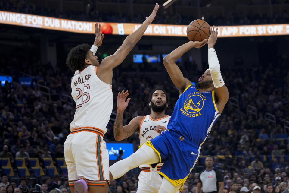 Golden State Warriors guard Moses Moody (4) shoots while defended by San Antonio Spurs forward Dominick Barlow during the first half of an NBA basketball game Saturday, March 9, 2024, in San Francisco. (AP Photo/Godofredo A. Vásquez)