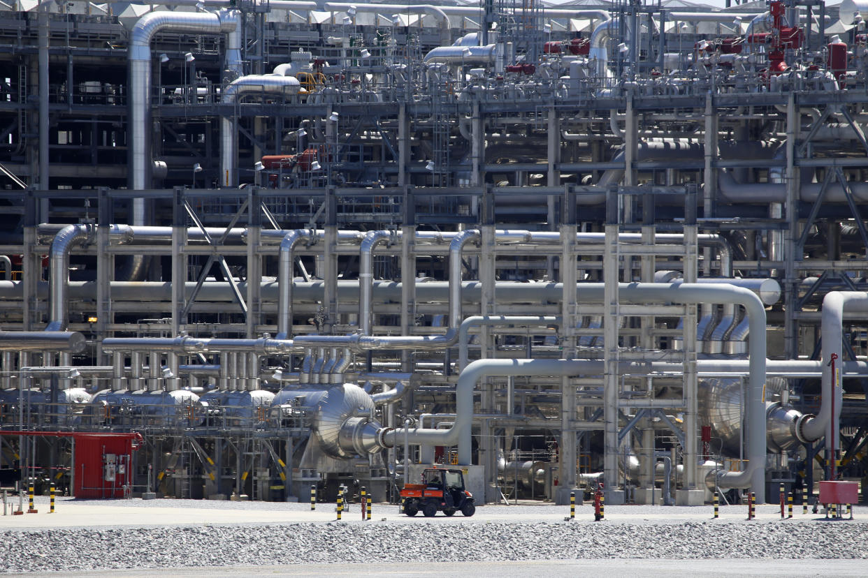 A small vehicle drives past a massive network of piping.