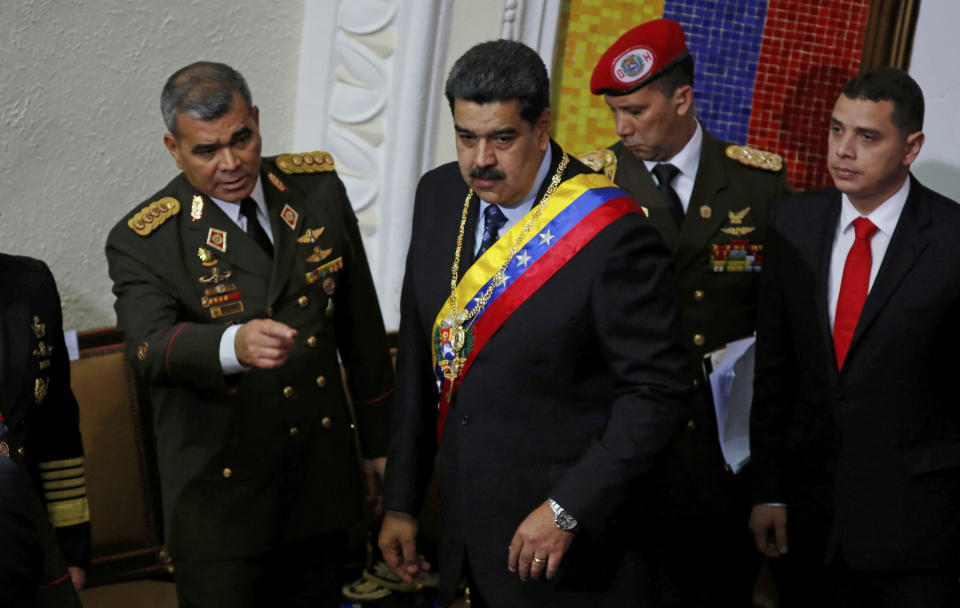 Venezuela's President Nicolas Maduro, center, stands with his Defense Minister Vladimir Padrino Lopez before giving his annual address to the nation to members of the Constitutional Assembly inside the National Assembly in Caracas, Venezuela, Monday, Jan. 14, 2019. (AP Photo/Ariana Cubillos)