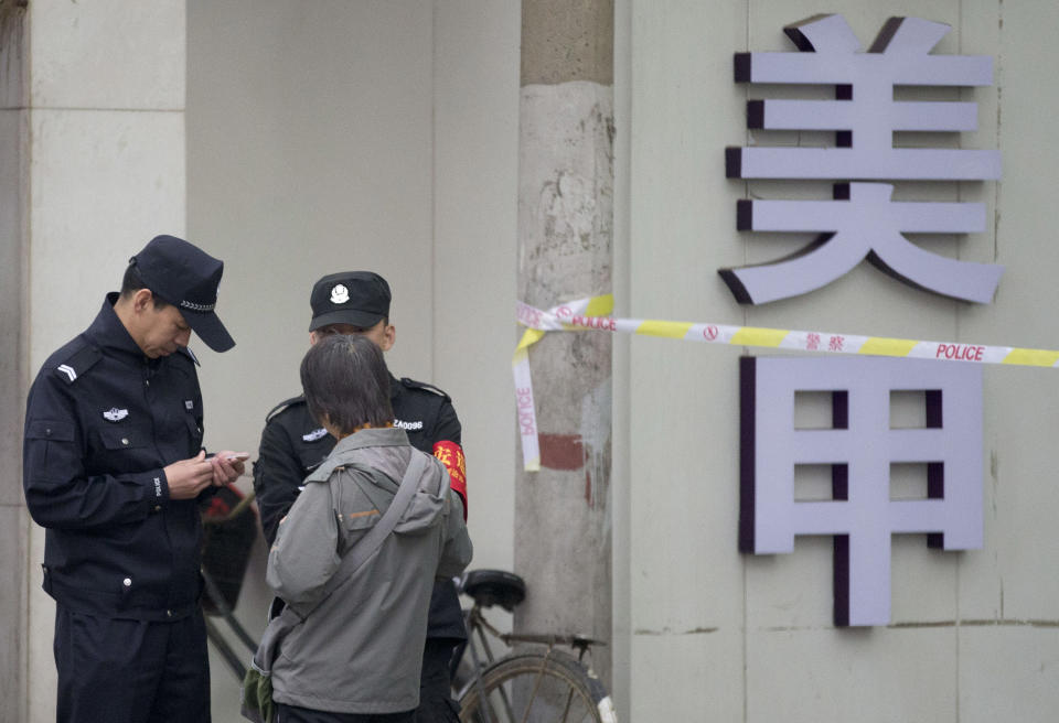 Chinese policemen check identification of a woman near the Beijing Supreme People's High Court where Xu Zhiyong, the founder of a Chinese grassroots movement, attends his case in Beijing, China Friday, April 11, 2014. The Beijing high court on Friday upheld a guilty verdict against Xu that promoted clean governance. (AP Photo/Andy Wong)