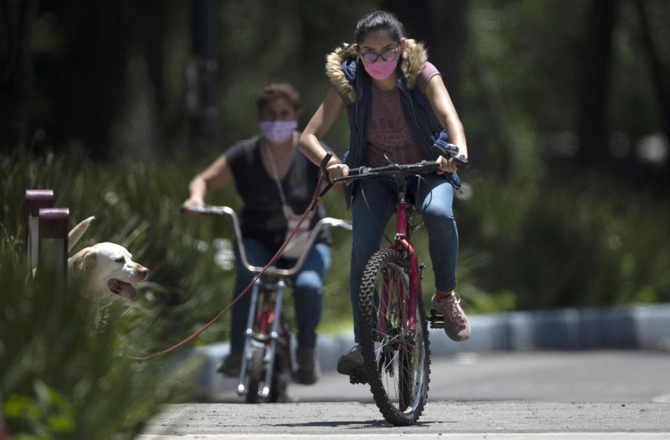 Riders wear masks to curb the spread of the new coronavirus in Chapultepec Park, Mexico City, Sunday, July 19, 2020. (AP Photo/Marco Ugarte)