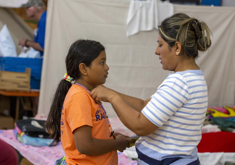 Karla, a Colombian migrant places a rosary necklace on her daughter Juanita, 9, inside a shelter at St. Francis Xavier Church in El Paso, Texas, Thursday, May 11, 2023. As confusion explodes in El Paso, one of the busiest illegal crossings points for migrants seeking to flee poverty and political strife, faith leaders continue to provide shelter, legal advice and prayer. (AP Photo/Andres Leighton)