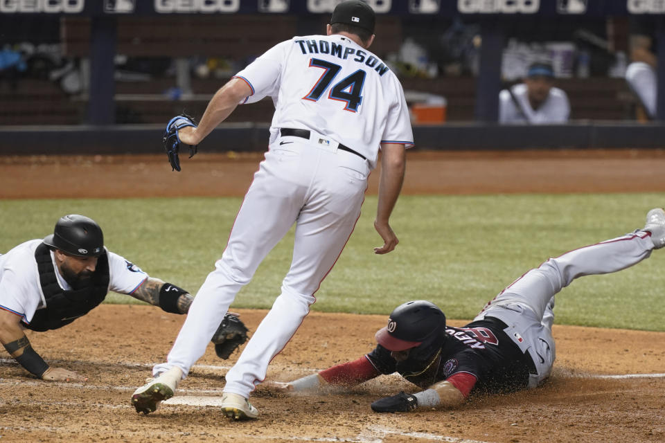 Miami Marlins' catcher Sandy Leon, left, stretches to tag Washington Nationals' Carter Kieboom (8) who was trying to score on a wild pitch while Marlins relief pitcher Zach Thompson (74) stands between them during the seventh inning of a baseball game, Monday, Sept. 20, 2021, in Miami. (AP Photo/Marta Lavandier)