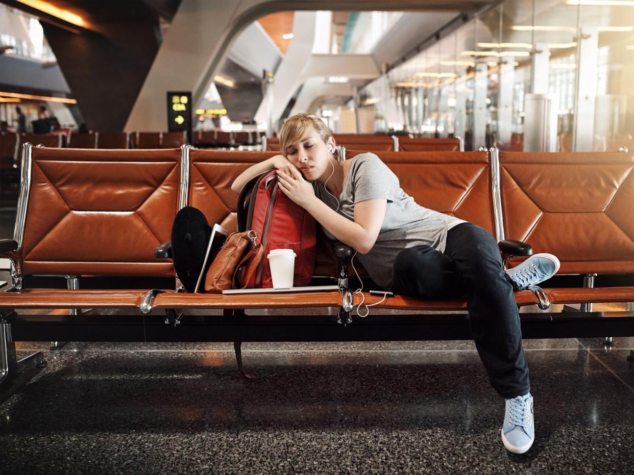 Full length shot of an attractive young woman sleeping in an airport