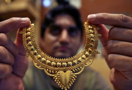 FILE PHOTO: A salesman poses with a gold necklace at a jewellery shop in Jammu July 11, 2008. REUTERS/Amit Gupta/File Photo