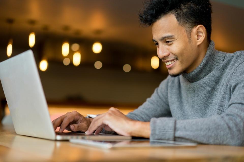 A person typing on a laptop while seated in a cafe.