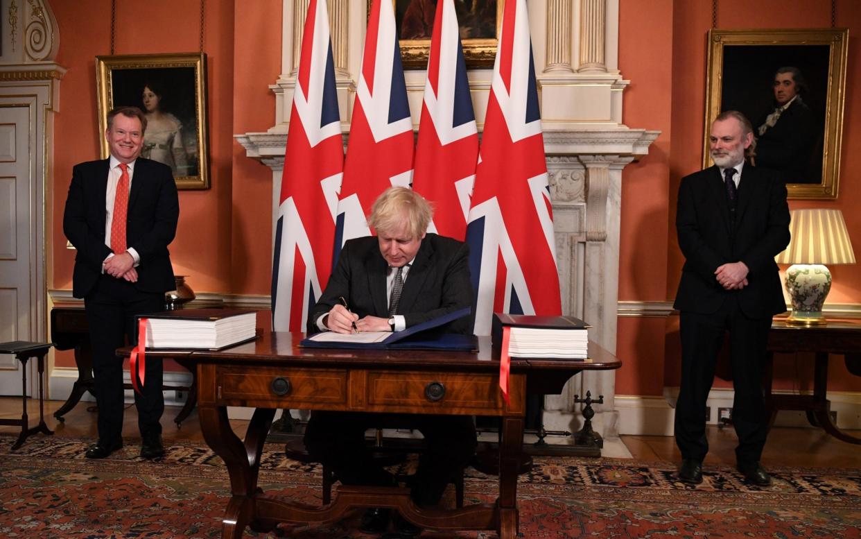 UK chief trade negotiator David Frost (L) and British Ambassador to the EU Tim Barrow (R) look on as Boris Johnson signs the Brexit trade deal with the EU  - Leon Neal/Getty Images Europe