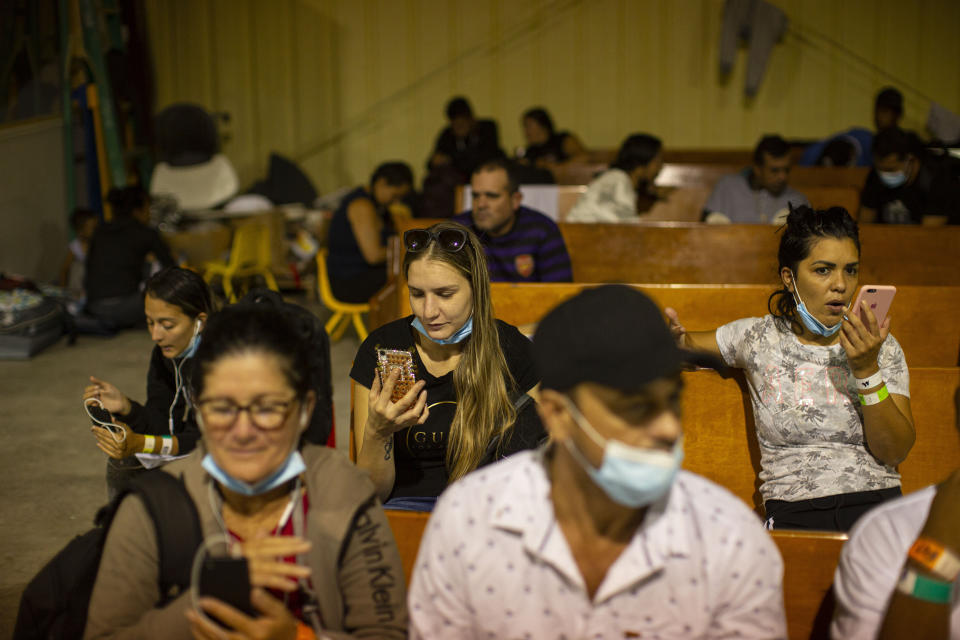 People wait and speak to relatives on their phones at a warehouse run by the Mission: Border Hope nonprofit group, in Eagle Pass, Texas, May 23, 2022. The Border Patrol releases up to 1,000 migrants daily at Mission: Border Hope. The nonprofit group, run by the United Methodist Church, outgrew a church and moved to the warehouse in April amid the Biden administration's rapidly expanding practice of releasing migrants on parole, particularly those who are not subject to a pandemic rule that prevents migrants from seeking asylum.(AP Photo/Dario Lopez-Mills)