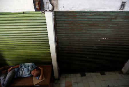 A man sleeps near next to a closed warehouse at Tanah Abang market in Jakarta at Tanah Abang market in Jakarta, Indonesia, September 6, 2018. REUTERS/Willy Kurniawan/Files