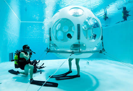 Belgians Florence Lutje Spelberg and Nicolas Mouchart dive into "The Pearl", a spheric dining room placed 5 metres underwater in the NEMO33 diving center, one of the world's deepest pools (33 metre/36 yards) built to train professional divers, before enjoying a meal inside, in Brussels, Belgium January 30, 2017. Picture taken January 30, 2017 REUTERS/Yves Herman