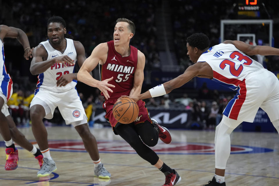 Miami Heat forward Duncan Robinson (55) drives between Detroit Pistons center Isaiah Stewart (28) andJaden Ivey (23) in the second half of an NBA basketball game in Detroit, Sunday, March 17, 2024. (AP Photo/Paul Sancya)