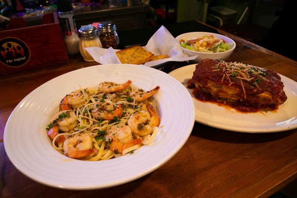 Plates of shrimp scampi and baked lasagna, along with garlic bread and a house salad, rest on the bar of Island Italian Restaurant on Thursday, Feb. 9, 2023.