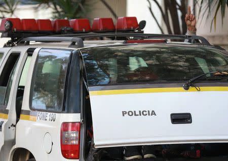 A detained man gestures in a police car before being transferred to a prison in Porto Alegre, Brazil September 11, 2018. REUTERS/Diego Vara/File Photo