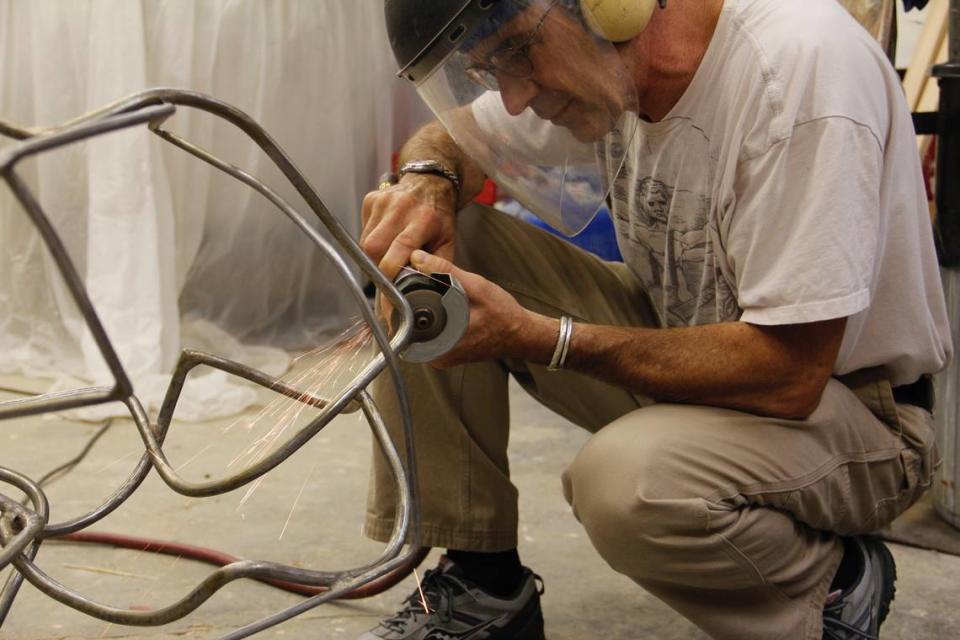 Artist Keith Bryant works in his home studio on a sculpture he later called “Inside Out.” He’s using an air grinder to smooth out a weld.