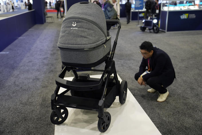 An attendee looks at the GluxKind Ella motorized smart stroller during the CES tech show Thursday, Jan. 5, 2023, in Las Vegas. (AP Photo/John Locher)