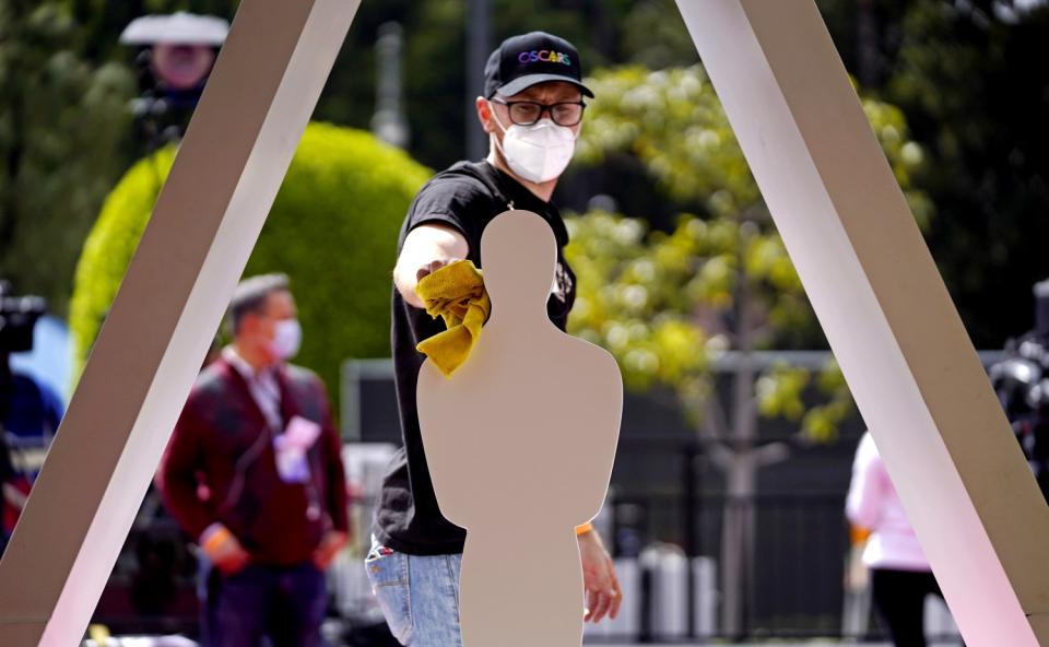 A man in a mask uses a cloth to clean a cutout.