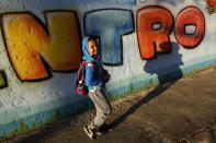 A student arrives for the first day back to in-person classes at a public school during the COVID-19 pandemic in Brasilia, Brazil, Thursday, Aug. 5, 2021, after a year and a half of remote learning. (AP Photo/Eraldo Peres)