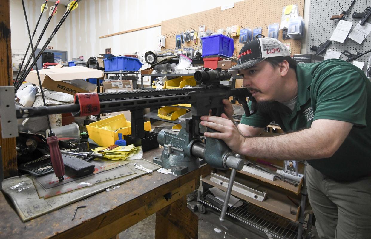 Logan Hill, a gunsmith and firearms salesman, looks down the scope of a rifle at H&H Shooting Sports in Oklahoma City. Hill graduated from Murray State College’s gunsmithing program.