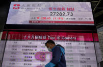 A man walks past a bank electronic board showing the Hong Kong share index at Hong Kong Stock Exchange Friday, Feb. 21, 2020. Asian stock markets have followed Wall Street lower after a rise in virus cases in South Korea refueled investor anxiety about China's disease outbreak.(AP Photo/Vincent Yu)