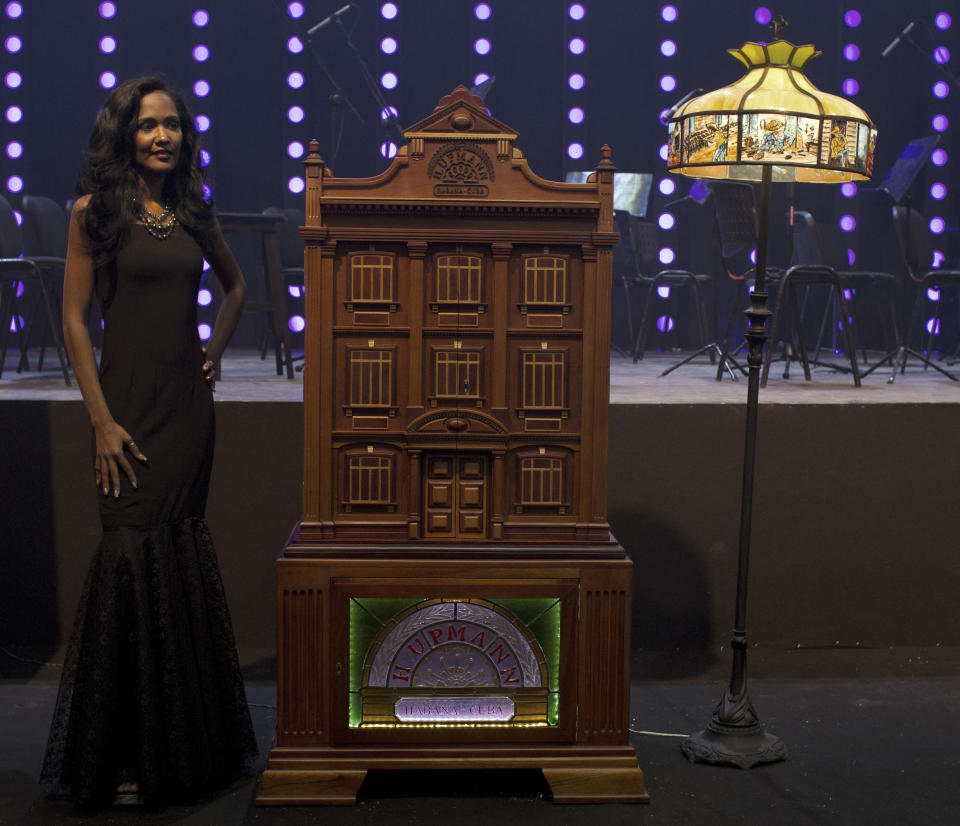 A model poses nest to a humidor during a gala dinner marking the end of the 16th annual Cigar Festival in Havana, Cuba, Friday, Feb. 28, 2014. Cigar enthusiasts paid more than $1.1 million dollars for six handmade Cuban humidors at the gala closing. (AP Photo/Franklin Reyes)