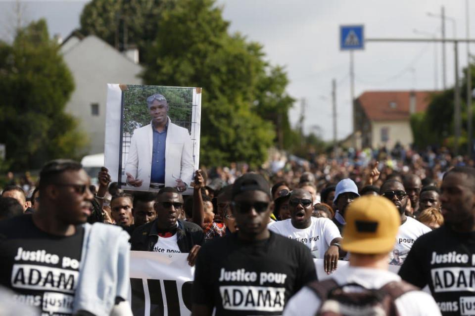 Des manifestants lèvent un portrait d'Adama Traoré en son hommage, en juillet 2018 à Beaumont-sur-Oise. FRANCOIS GUILLOT / AFP - THOMAS SAMSON / AFP