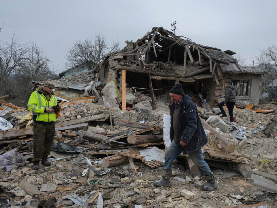 Villagers walk in the debris of private houses ruined in Russia's night rocket attack in a village, in Zolochevsky district in the Lviv region, Ukraine, Thursday, March 9, 2023.