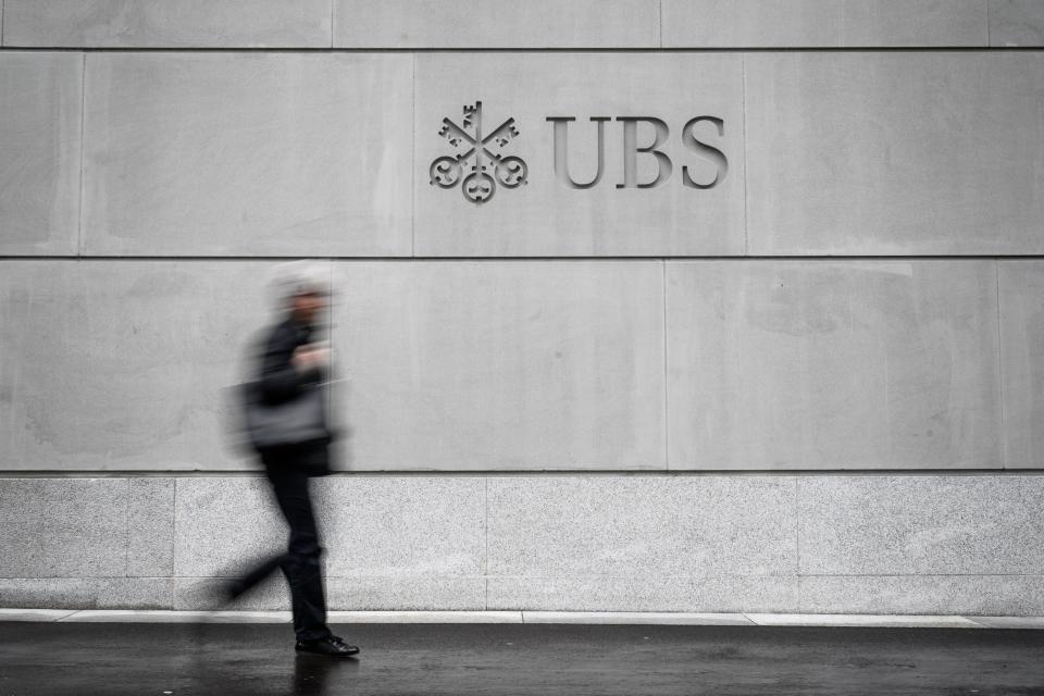 A pedestrian walks by the logo of Swiss banking giant UBS engraved on the wall of its headquarters on May 8, 2019 in Zurich. (Photo by Fabrice COFFRINI / AFP)        (Photo credit should read FABRICE COFFRINI/AFP/Getty Images)