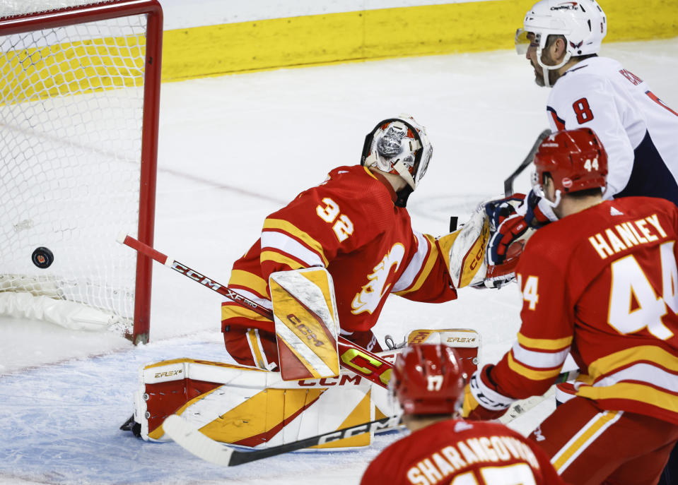 Washington Capitals forward Alex Ovechkin (8) scores against Calgary Flames goalie Dustin Wolf (32) during second-period NHL hockey game action in Calgary, Alberta, Monday, March 18, 2024. (Jeff McIntosh/The Canadian Press via AP)