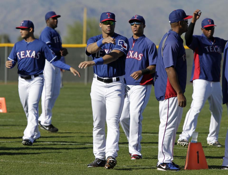 Seattle Seahawks quarterback Russell Wilson, center, runs through morning stretches with the Texas Rangers during spring training baseball practice, Monday, March 3, 2014, in Surprise, Ariz. (AP Photo/Tony Gutierrez)