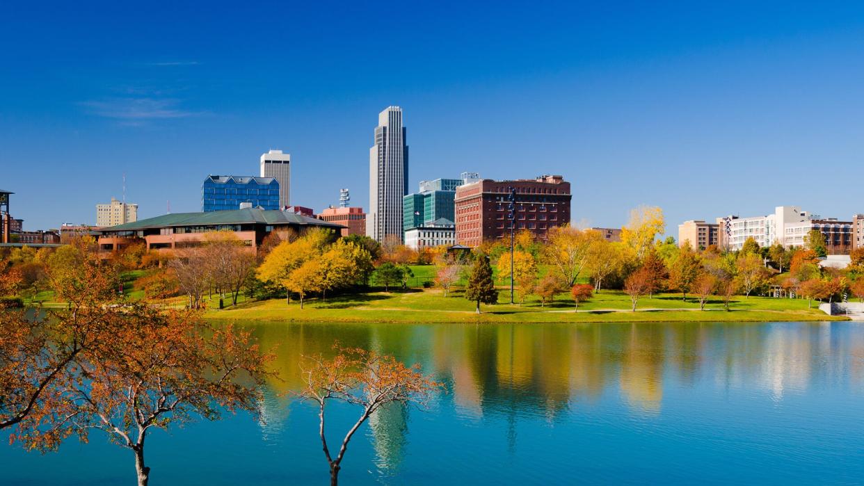 Downtown Omaha skyline with the Heartland of America Park (with a lake and fall colored trees) in the foreground.