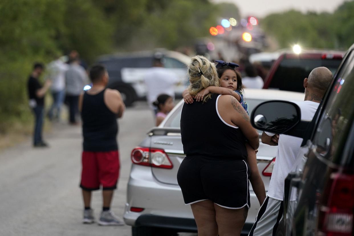 Onlookers stand near the scene where a semitrailer with multiple dead bodies was discovered on Monday, June 27, 2022, in San Antonio.