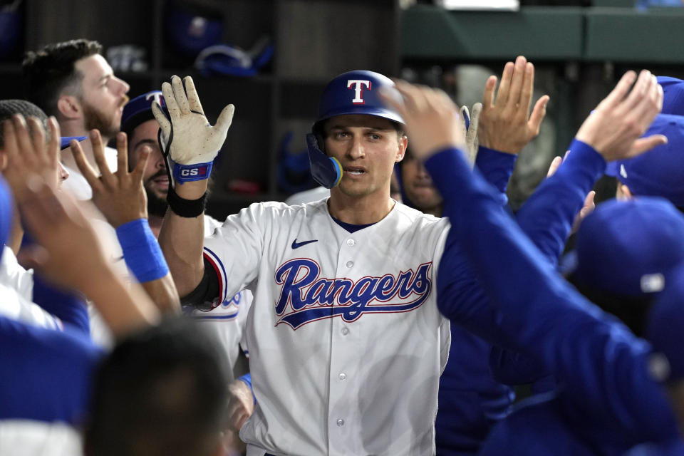 Texas Rangers' Corey Seager celebrates in the dugout after hitting a home run against the Houston Astros during the third inning in Game 4 of the baseball American League Championship Series Thursday, Oct. 19, 2023, in Arlington, Texas. (AP Photo/Julio Cortez)