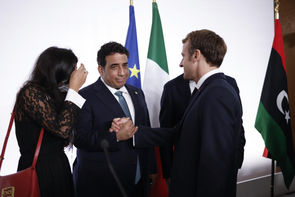 French President Emmanuel Macron, right, greets head of the Presidential Council of Libya Mohamed al-Manfi after a conference on Libya in Paris Friday, Nov. 12, 2021. France is hosting an international conference on Libya on Friday as the North African country is heading into long-awaited elections next month. (Yoan Valat/Pool Photo via AP)