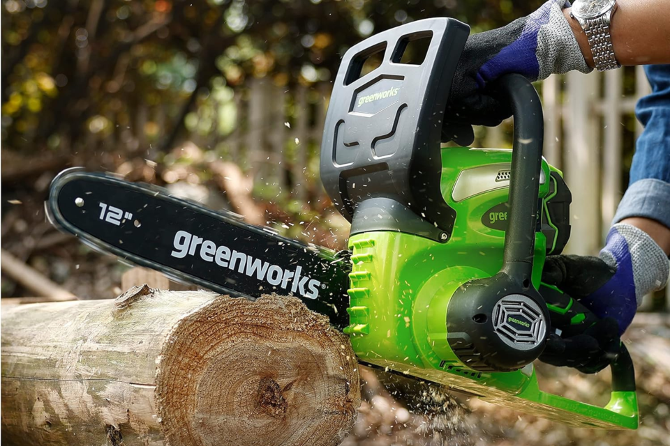 someone uses a Greenworks chainsaw to cut a log