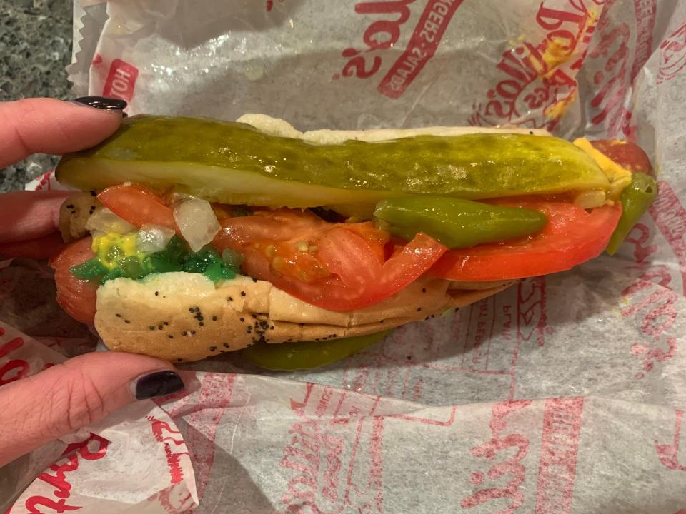 hand picking up a loaded chicago style hotdog off a portillos wrapper