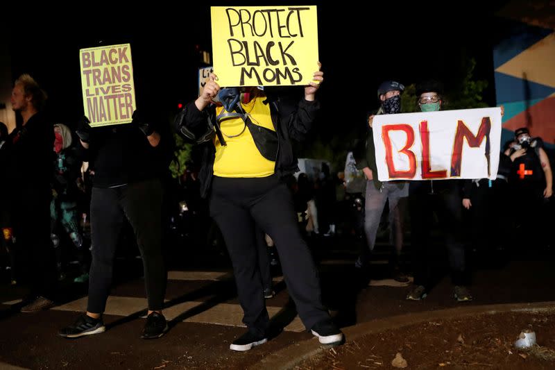 FILE PHOTO: Demonstrators hold signs during a protest against police violence and racial injustice in Portland