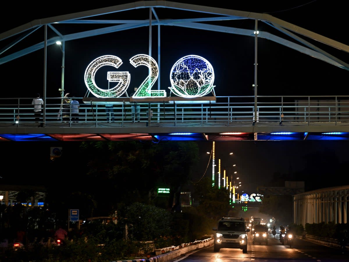 Vehicles ride under an illuminated hoarding with the G20 logo displayed over a bridge in New Delhi (AFP via Getty Images)