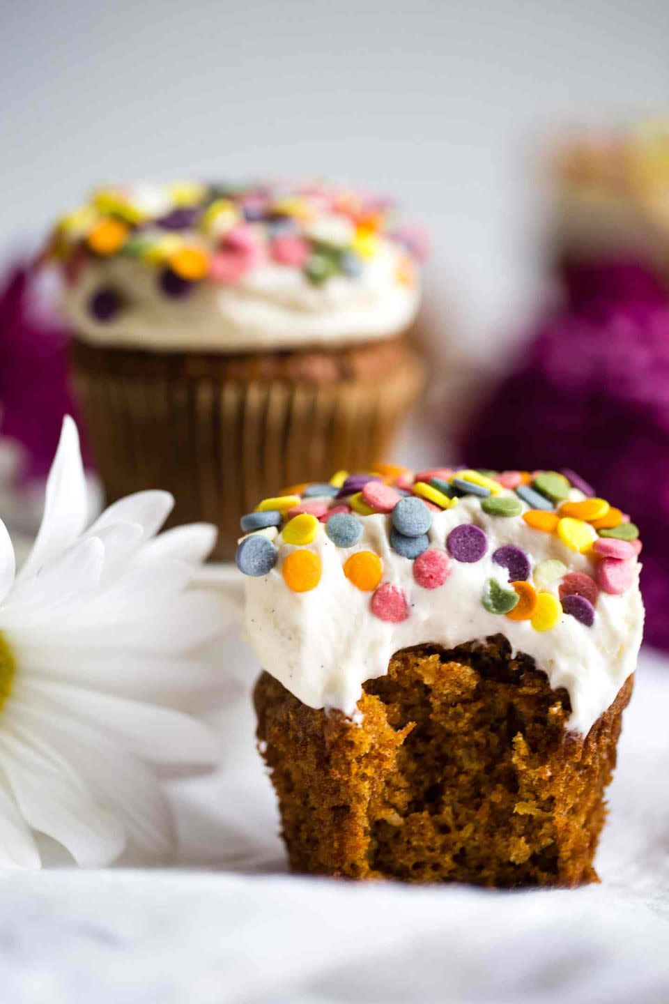 carrot cake cupcake with white frosting and rainbow sprinkles