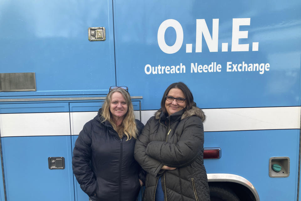 Anne Muilenburg, right, and Debra Cross, employees of the addiction recovery center Provoking Hope, pose for a photo Thursday, Dec. 9, 2021, in front of an ambulance converted into a mobile needle-exchange unit in McMinnville, Ore. Workers for the organization try to get people addicted to drugs off them. Those not ready to quit can get clean syringes to replace contaminated ones. McMinnville and thousands of other towns across the United States that were wracked by the opioid crisis are on the precipice of receiving billions of dollars in the second-biggest legal settlement in U.S. history. (AP Photo/Andrew Selsky)