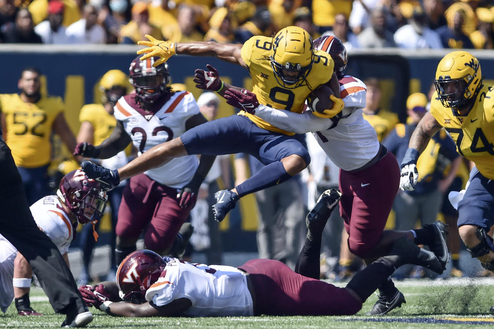 West Virginia wide receiver Isaiah Esdale (9) leaps over a Virginia Tech player during the first half of an NCAA college football game in Morgantown, W.Va., Saturday, Sept. 18, 2021. (AP Photo/William Wotring)