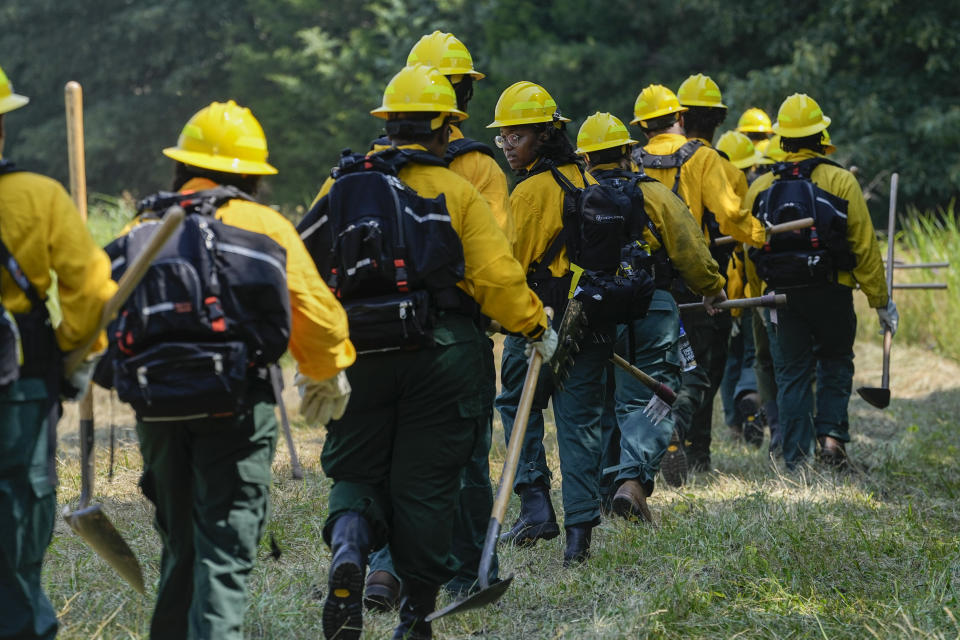 Earielle London looks back as she and other students from Alabama A&M and Tuskegee Universities march into the woods for a wildland firefighter training Friday, June 9, 2023, in Hazel Green, Ala. A partnership between the U.S. Forest Service and four historically Black colleges and universities is opening the eyes of students of color who had never pictured themselves as fighting forest fires. (AP Photo/George Walker IV)