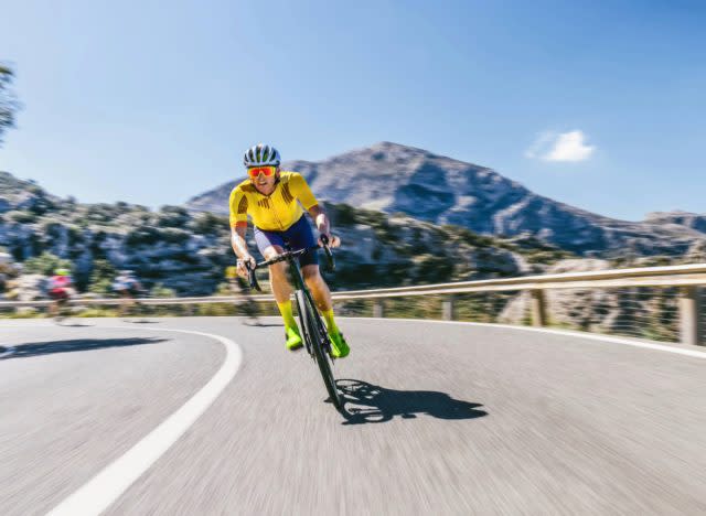 fit man biking through roads in the mountains on sunny day